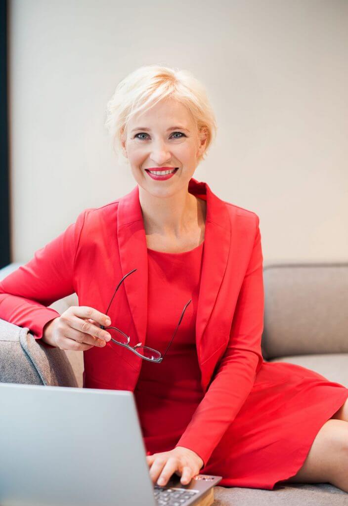 Katrin Friedel Botschafterin für Glück im roten Kleid am Laptop