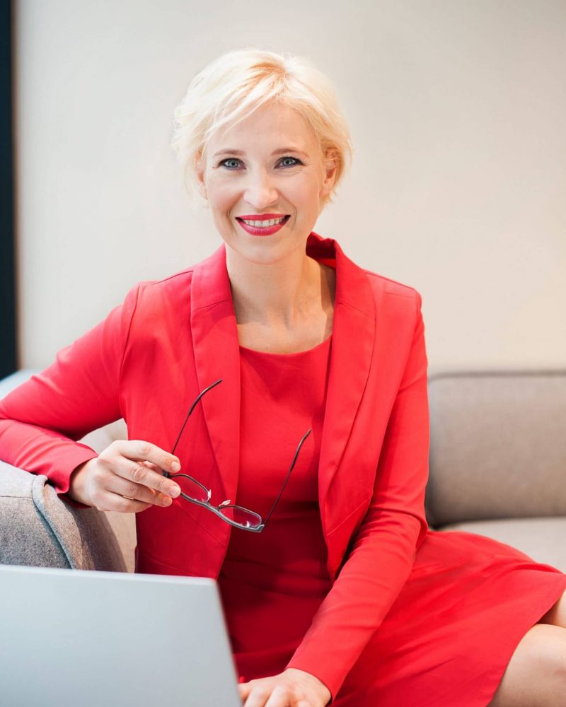 Katrin Friedel Botschafterin für Glück im roten Kleid am Laptop